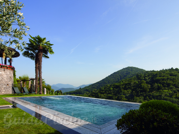 Piscina con sfioro in granito, vasca in vetroresina, copertura tapparella e controcorrente