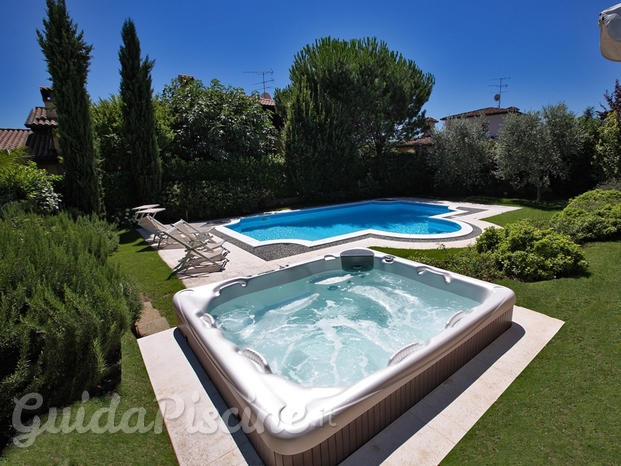 Minispiscina Spa in un giardino con piscina sullo sfondo